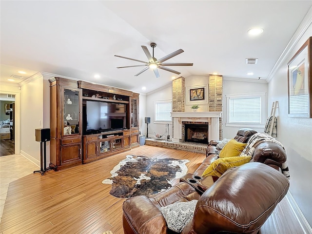 living room with crown molding, lofted ceiling, light hardwood / wood-style floors, and a brick fireplace