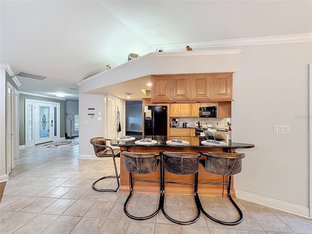 kitchen with light tile patterned flooring, a kitchen bar, kitchen peninsula, and black appliances