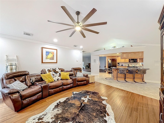 living room with ornamental molding, lofted ceiling, ceiling fan, and light hardwood / wood-style flooring