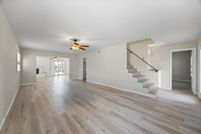 7886 9th Ave S, Saint Petersburg, FL 33707 - unfurnished living room featuring a ceiling fan, light wood-style flooring, stairway, and baseboards
