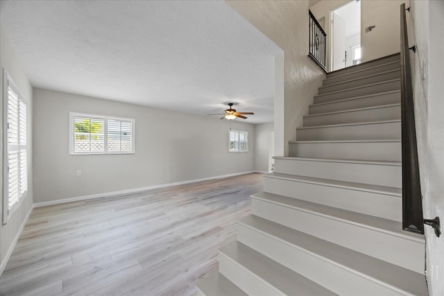 7886 9th Ave S, Saint Petersburg, FL 33707 - stairs featuring ceiling fan, wood finished floors, and baseboards