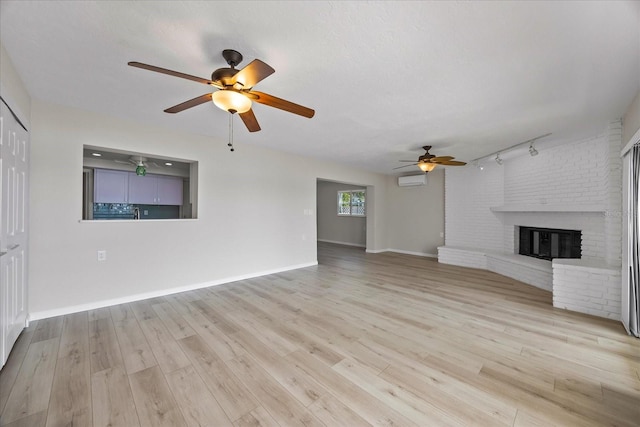 7886 9th Ave S, Saint Petersburg, FL 33707 - unfurnished living room featuring ceiling fan, a wall unit AC, wood finished floors, a brick fireplace, and rail lighting