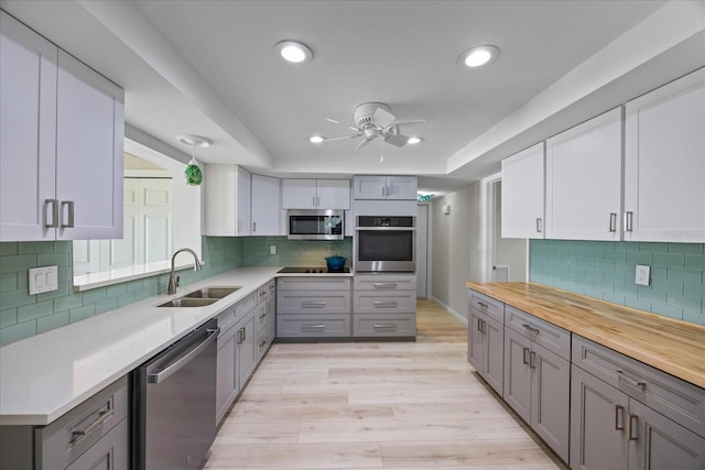 7886 9th Ave S, Saint Petersburg, FL 33707 - kitchen with appliances with stainless steel finishes, a sink, gray cabinets, a ceiling fan, and tasteful backsplash