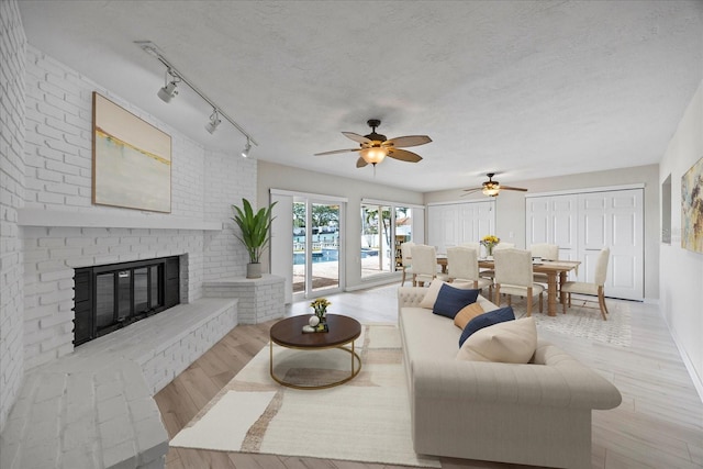 7886 9th Ave S, Saint Petersburg, FL 33707 - living area with wood finished floors, a ceiling fan, a fireplace, and rail lighting