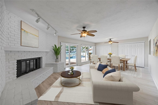 7886 9th Ave S, Saint Petersburg, FL 33707 - living room with wood finished floors, a ceiling fan, a brick fireplace, and track lighting