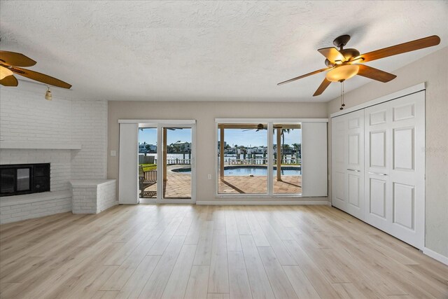 7886 9th Ave S, Saint Petersburg, FL 33707 - unfurnished living room featuring ceiling fan, wood finished floors, a textured ceiling, and a fireplace