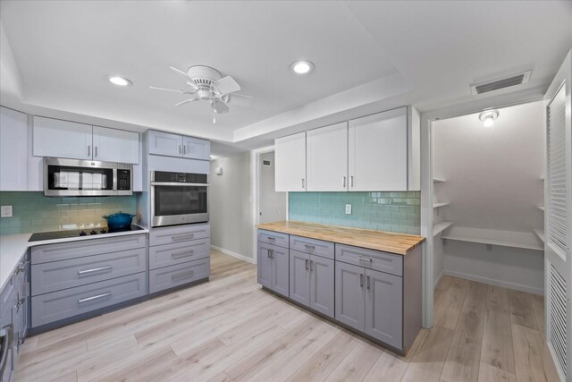7886 9th Ave S, Saint Petersburg, FL 33707 - kitchen featuring stainless steel appliances, gray cabinets, a tray ceiling, wood counters, and a ceiling fan