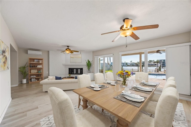 7886 9th Ave S, Saint Petersburg, FL 33707 - dining room featuring a wall mounted AC, ceiling fan, a water view, and a brick fireplace