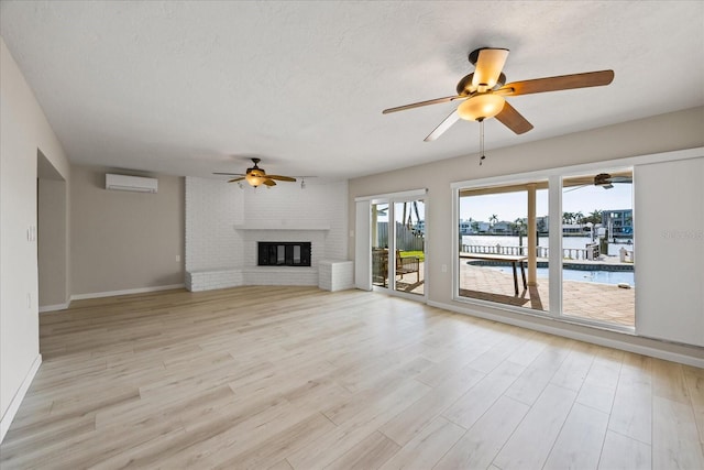 7886 9th Ave S, Saint Petersburg, FL 33707 - unfurnished living room featuring ceiling fan, an AC wall unit, a water view, light wood-type flooring, and a fireplace