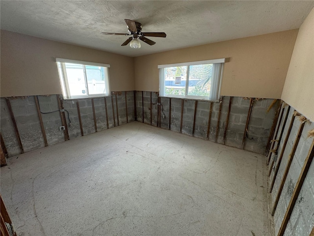 unfurnished room with a textured ceiling, a healthy amount of sunlight, and ceiling fan