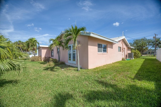 view of side of home featuring central air condition unit and a lawn