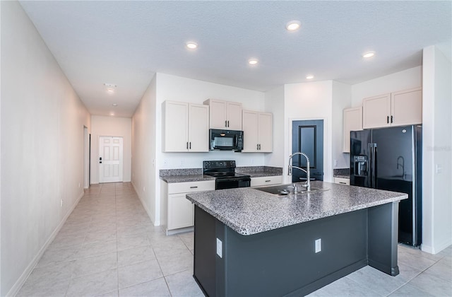 kitchen featuring light tile patterned floors, black appliances, a sink, baseboards, and a center island with sink