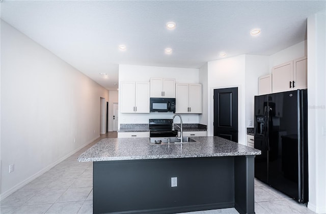 kitchen with white cabinets, an island with sink, black appliances, stone countertops, and sink