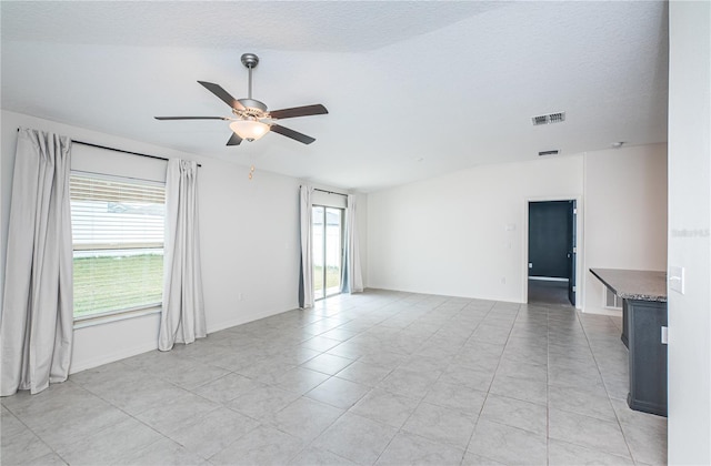 tiled spare room with ceiling fan, a textured ceiling, and a wealth of natural light