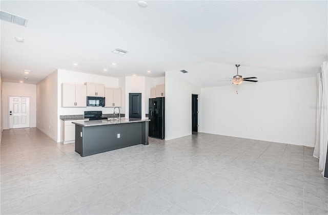 kitchen with light stone counters, ceiling fan, an island with sink, black appliances, and sink