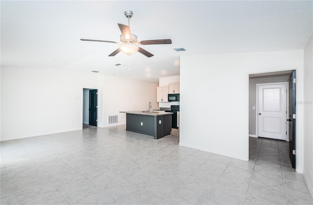 unfurnished living room featuring light tile patterned floors, ceiling fan, visible vents, and a sink