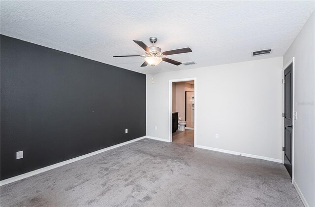 unfurnished bedroom with a textured ceiling, visible vents, carpet, and baseboards