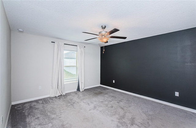 empty room with a textured ceiling, ceiling fan, baseboards, and carpet floors