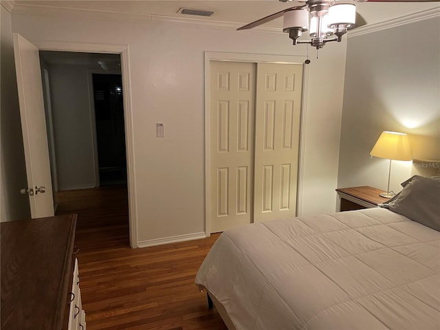 bedroom featuring ornamental molding, a closet, ceiling fan, and dark wood-type flooring