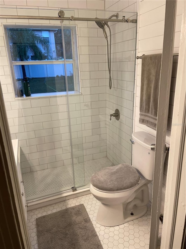 bathroom featuring tile patterned flooring, toilet, and a shower with shower door