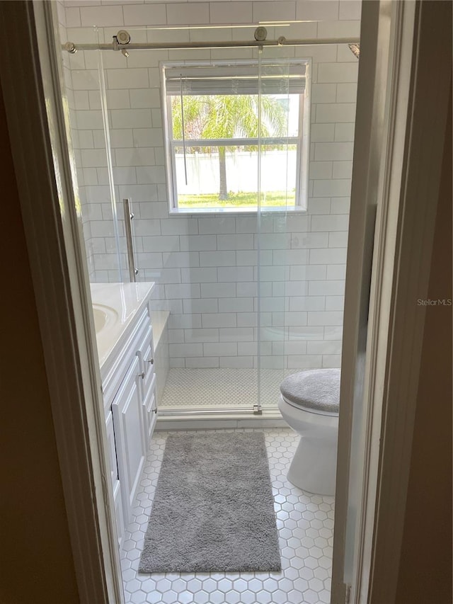 bathroom with tile patterned flooring, vanity, a shower with shower door, and toilet