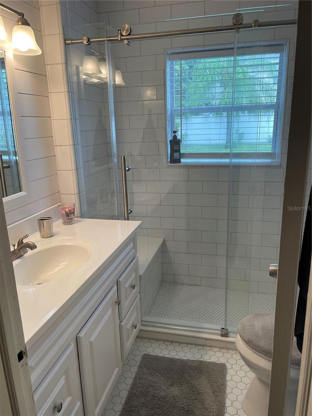 bathroom with tile patterned floors, vanity, an enclosed shower, and toilet