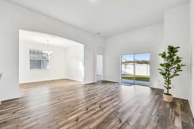 unfurnished living room with a chandelier and light wood-type flooring