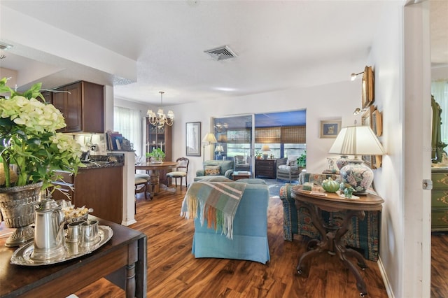 living room featuring dark wood-type flooring, a notable chandelier, and a textured ceiling