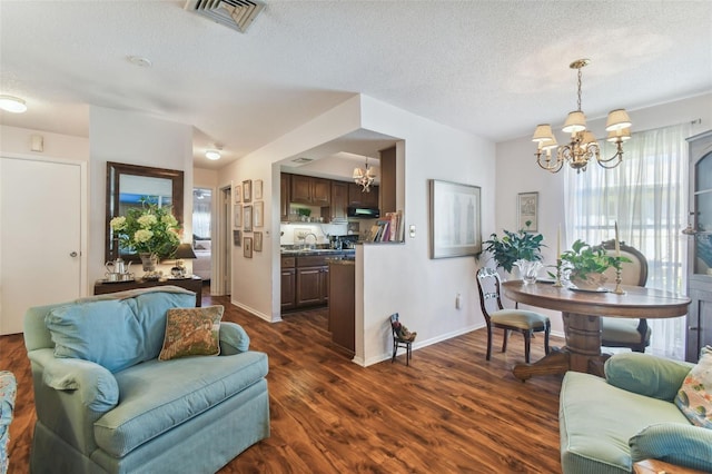 living room featuring sink, a textured ceiling, an inviting chandelier, and dark hardwood / wood-style flooring