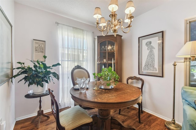 dining space featuring an inviting chandelier, a textured ceiling, and dark wood-type flooring