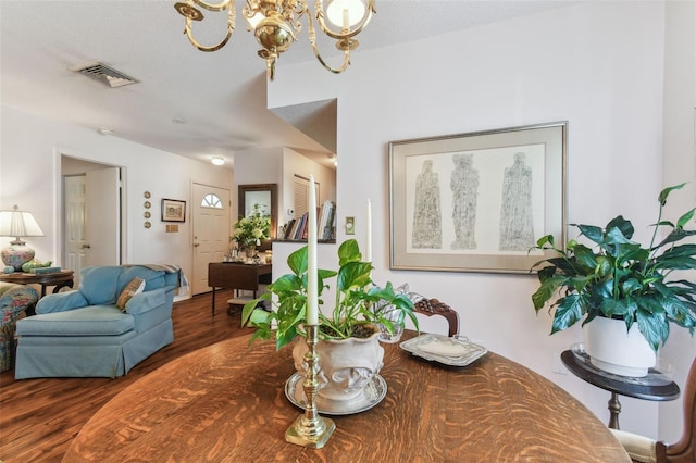 dining area with dark wood-type flooring, a notable chandelier, and a textured ceiling