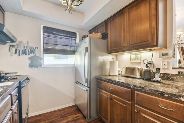 kitchen featuring appliances with stainless steel finishes, a textured ceiling, a tray ceiling, and dark wood-type flooring