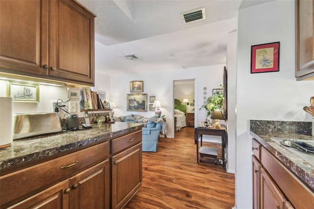 kitchen featuring dark hardwood / wood-style floors, dark stone countertops, and a textured ceiling