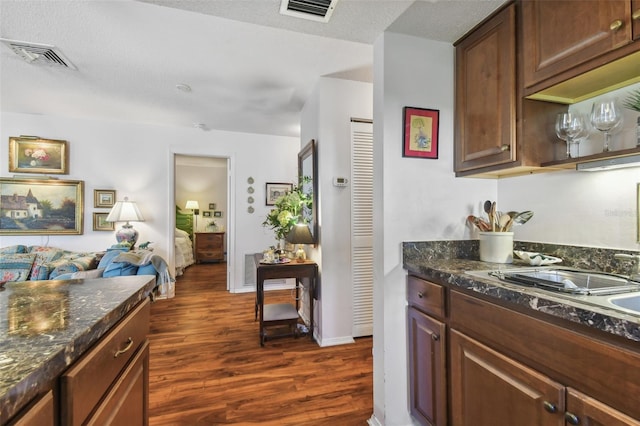 kitchen with dark stone counters, a textured ceiling, and dark hardwood / wood-style flooring