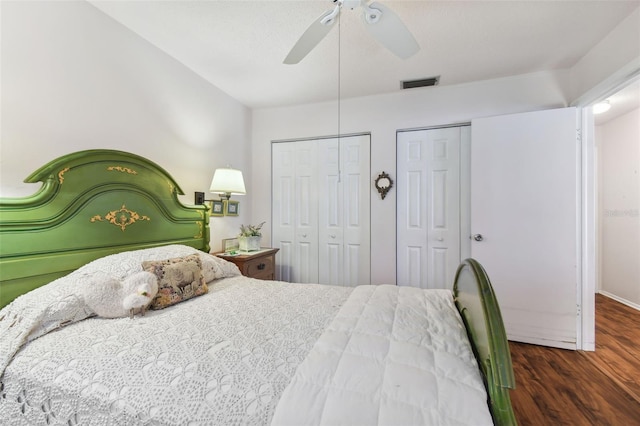 bedroom featuring dark hardwood / wood-style flooring, two closets, and ceiling fan