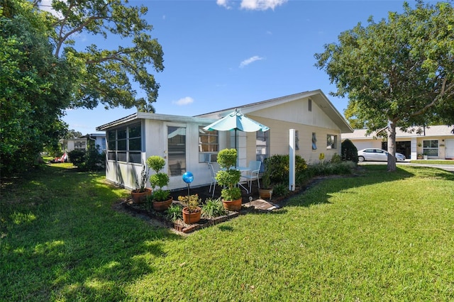 view of side of property with a sunroom and a lawn