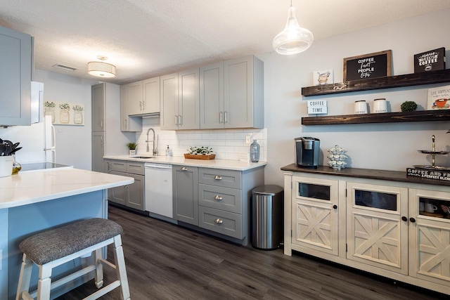 kitchen with gray cabinets, dark wood-type flooring, pendant lighting, and white appliances