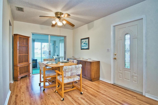 dining room with a textured ceiling, light wood-type flooring, and ceiling fan