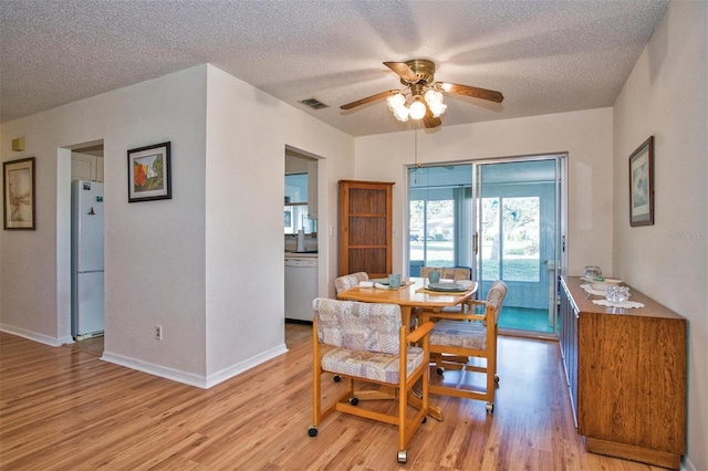 dining room featuring a textured ceiling, light wood-type flooring, and ceiling fan