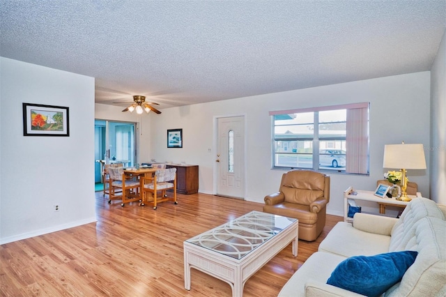 living room featuring a textured ceiling, light wood-type flooring, and ceiling fan