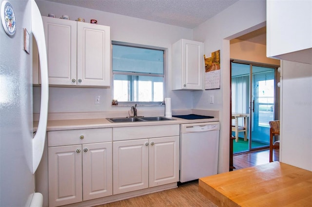 kitchen with white appliances, sink, a wealth of natural light, and white cabinets