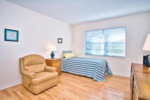 bedroom with light hardwood / wood-style floors and a textured ceiling