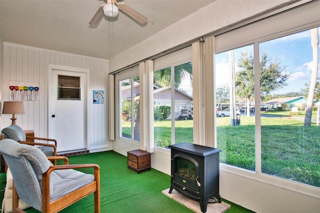 sunroom with ceiling fan, a wood stove, and plenty of natural light