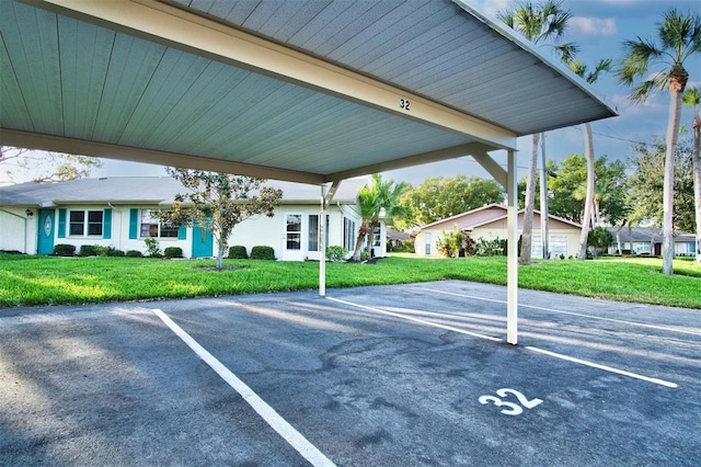 view of parking / parking lot with a carport and a lawn