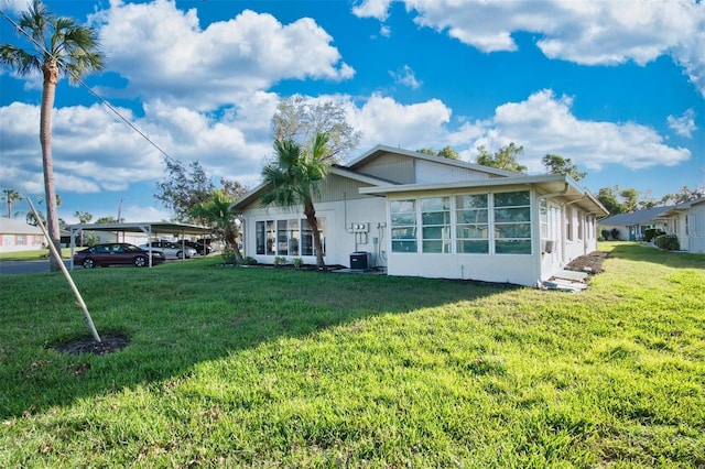 rear view of property with a lawn and a carport