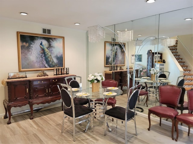 dining space with light hardwood / wood-style flooring and a notable chandelier