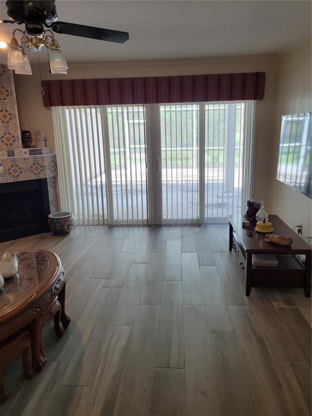 living room featuring hardwood / wood-style flooring, a tile fireplace, and ceiling fan