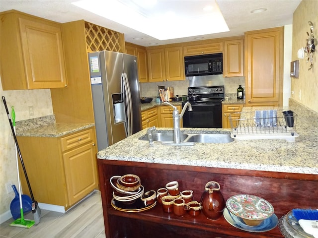 kitchen featuring sink, light stone countertops, black appliances, and light hardwood / wood-style flooring