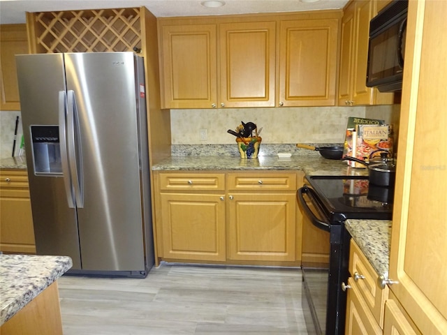 kitchen featuring light hardwood / wood-style flooring, light stone countertops, black appliances, and tasteful backsplash