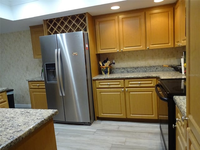 kitchen with black electric range, light stone countertops, light hardwood / wood-style flooring, and stainless steel refrigerator with ice dispenser